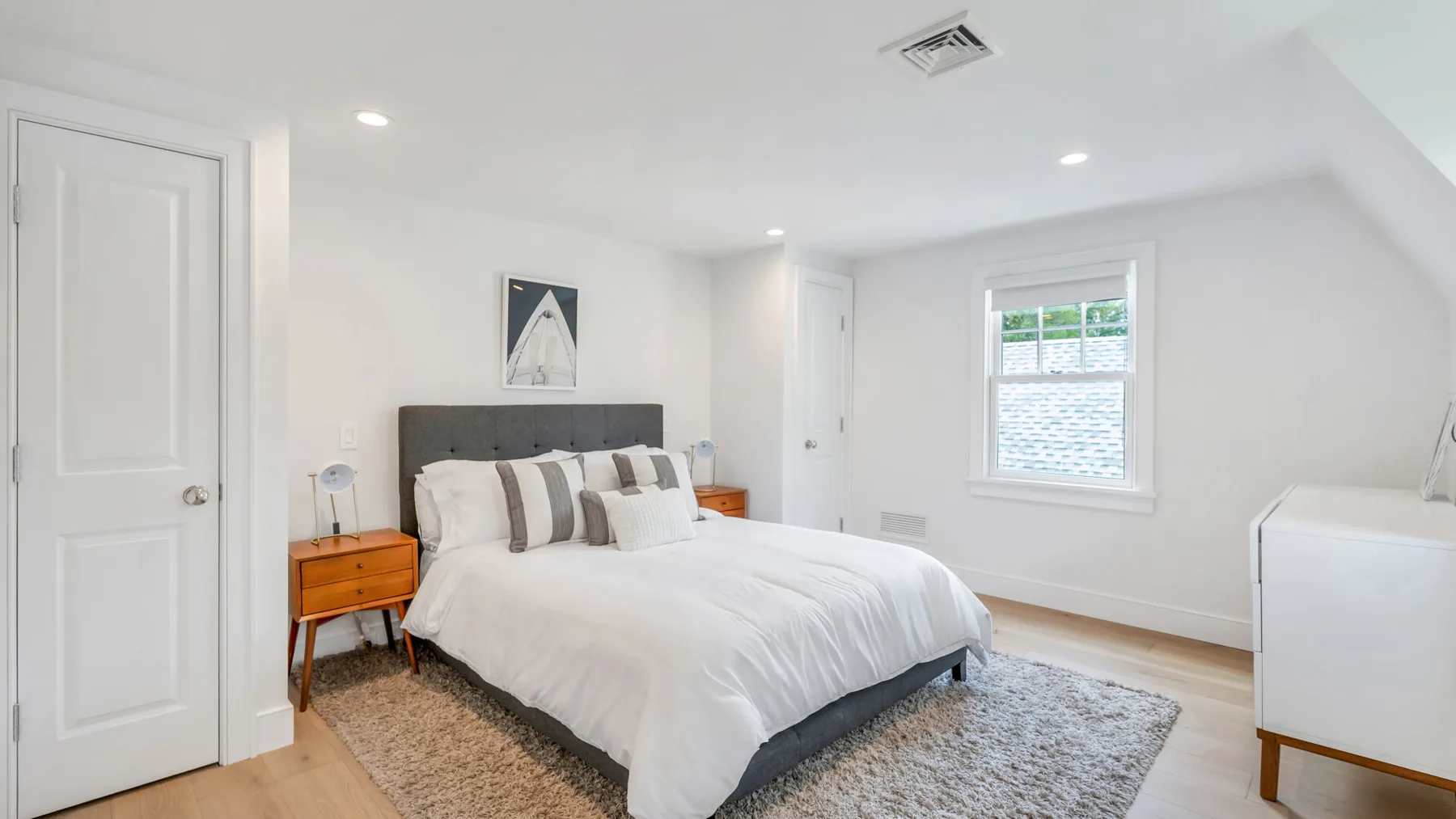 A bright bedroom with a neatly made bed and a window.