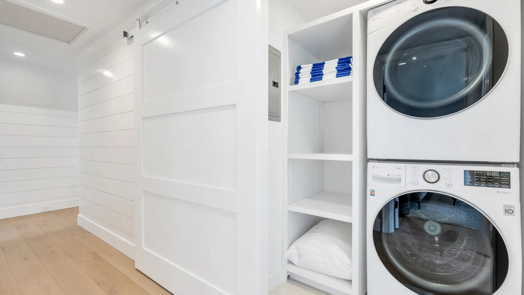 A laundry area with a stacked washer and dryer beside open shelving.