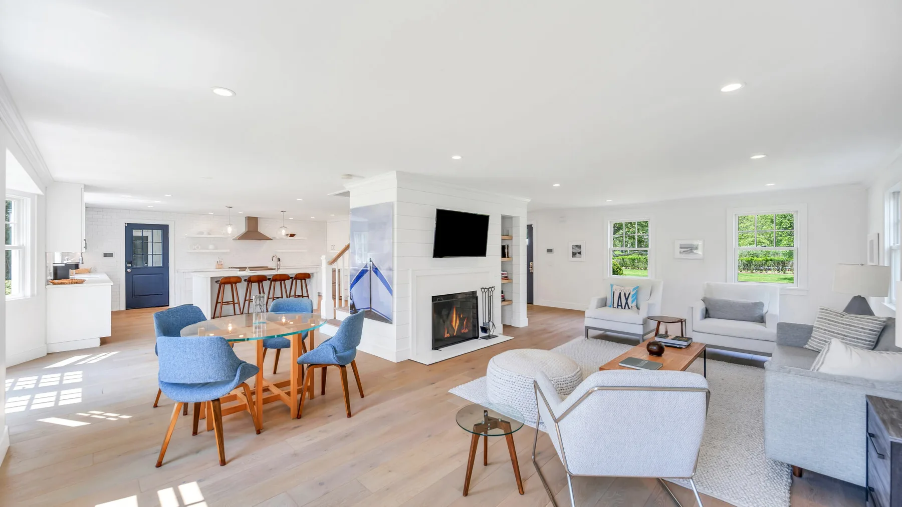 A bright open-plan living and dining area with seating, a table, and a fireplace.