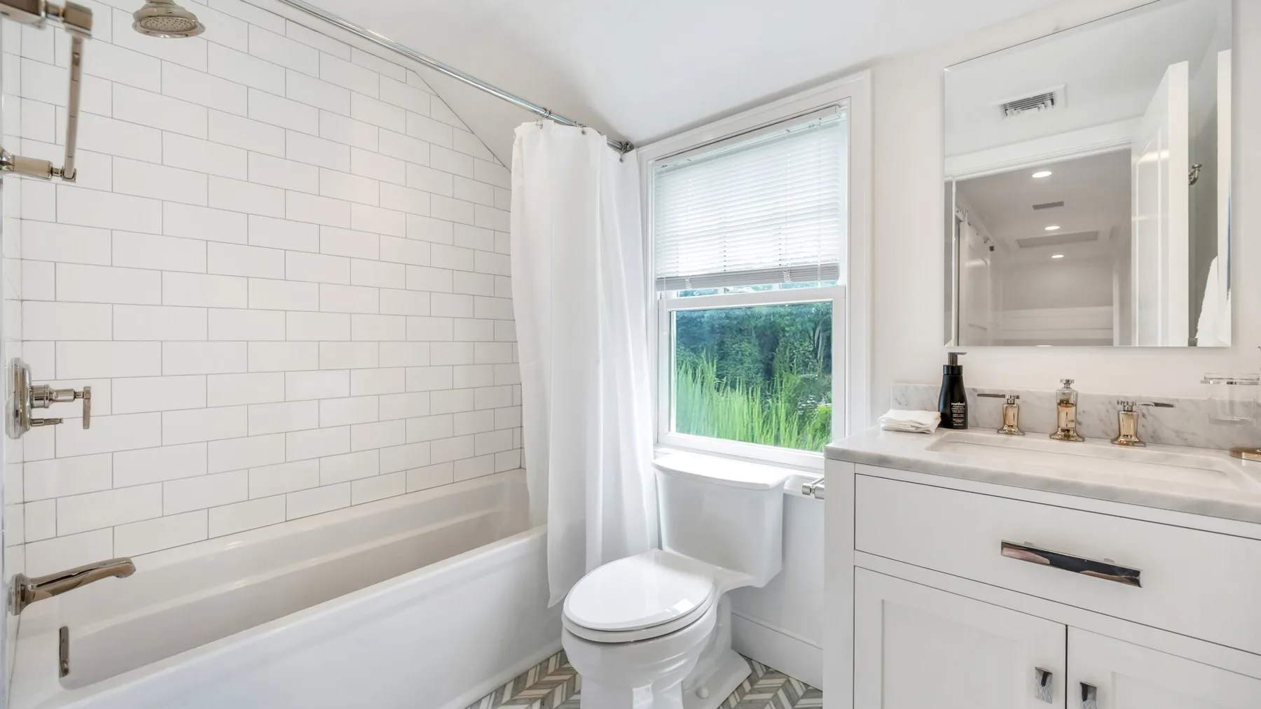 A bright bathroom with a bathtub, shower curtain, and vanity.