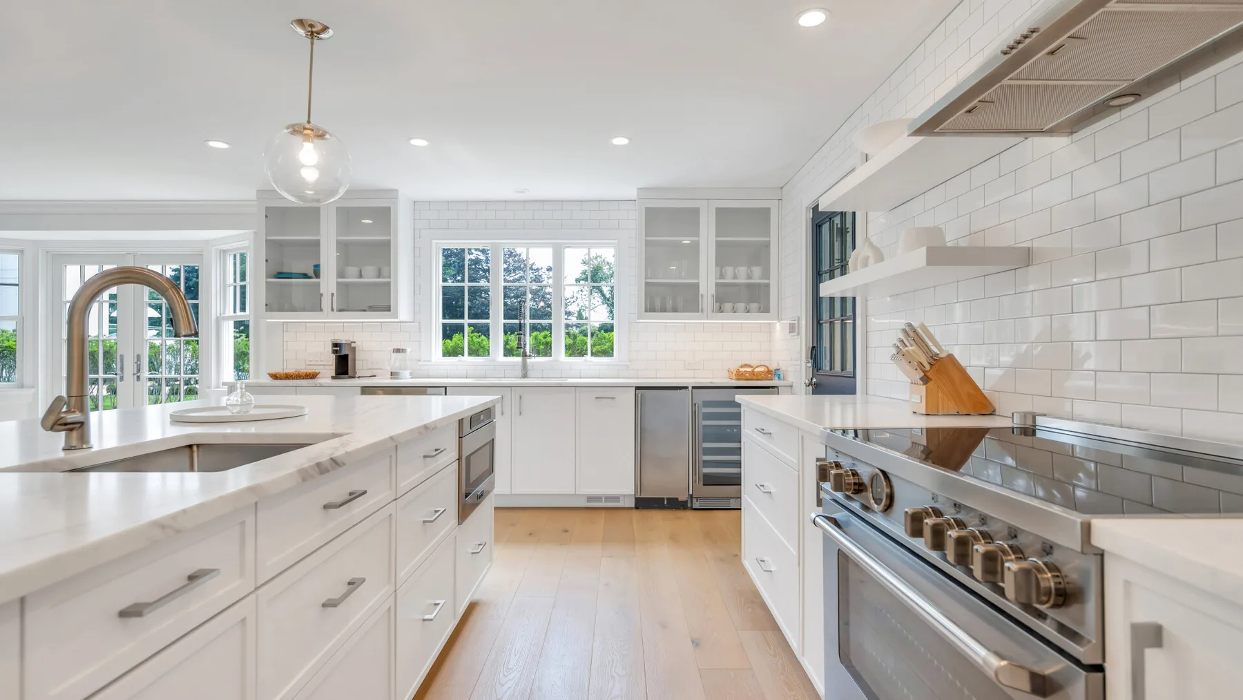 A bright white kitchen with a central island and stainless steel appliances.