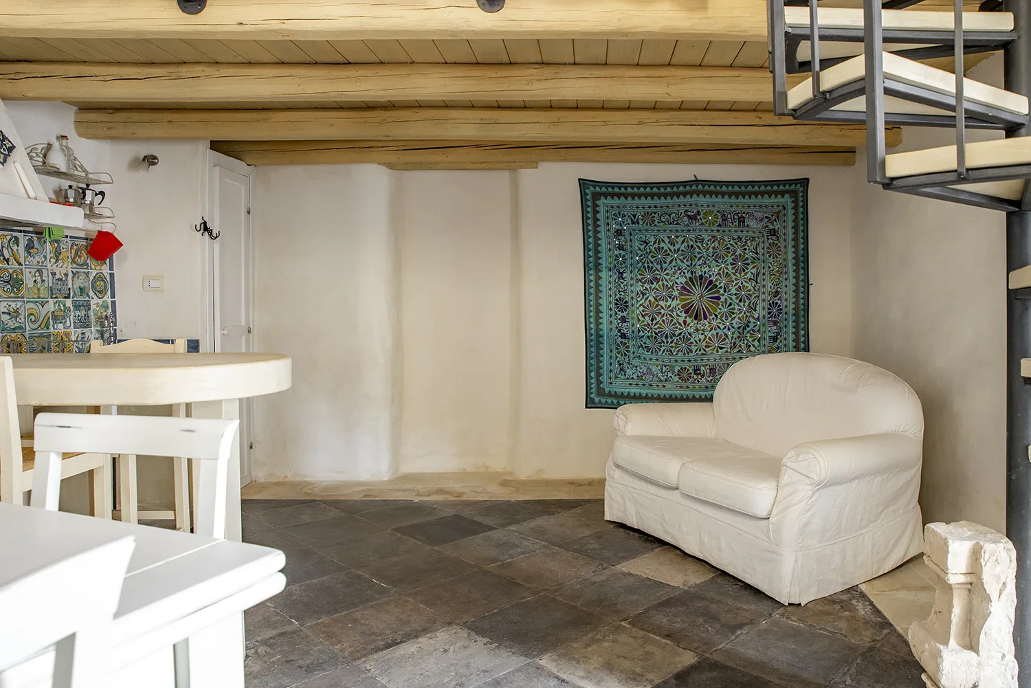 A compact living area with white seating beneath a low wooden ceiling.