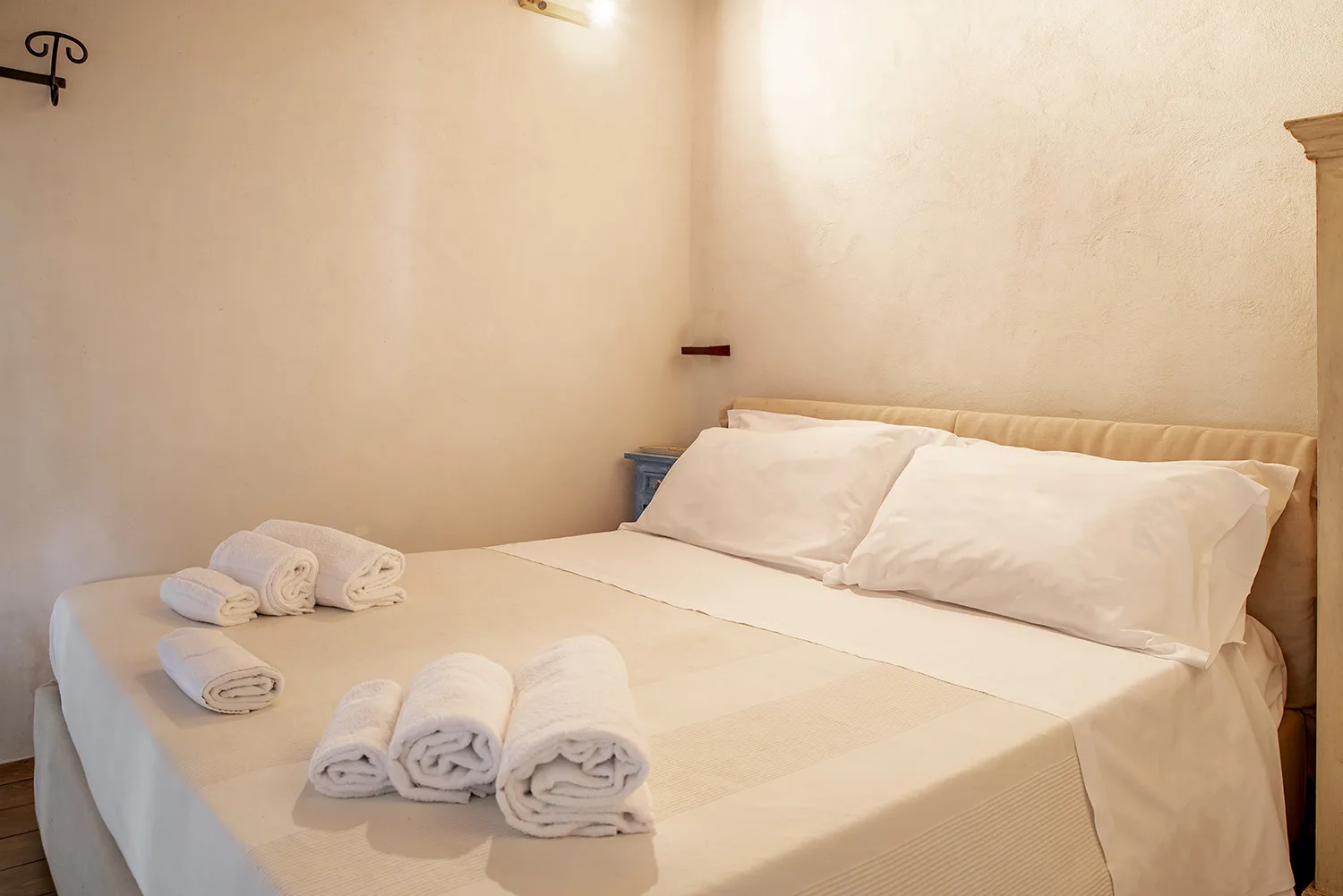 A bedroom with a neatly made bed and folded towels.