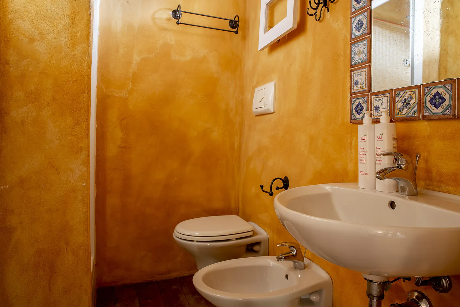 A warm-toned bathroom with a sink, toilet, and bidet.