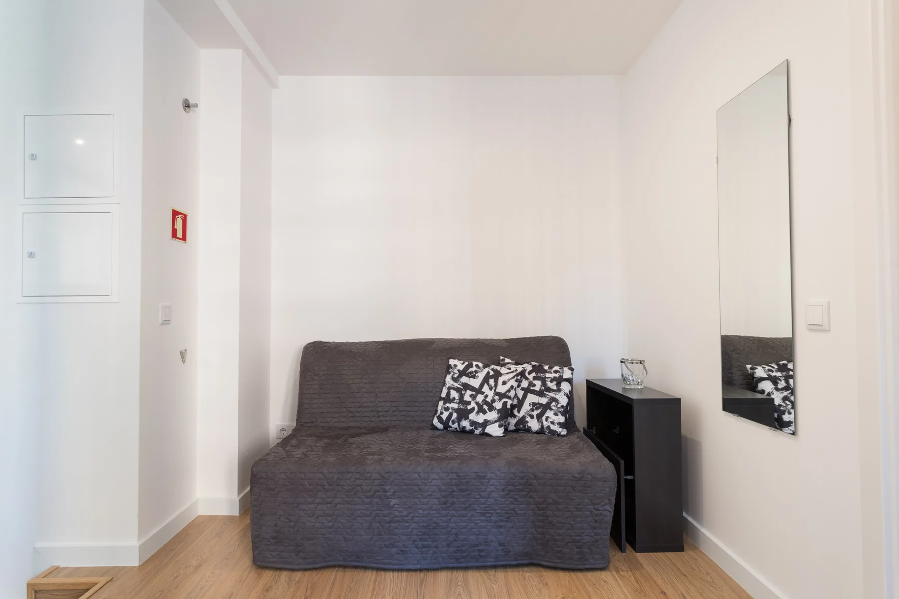 A small living area with a dark sofa and patterned cushions.