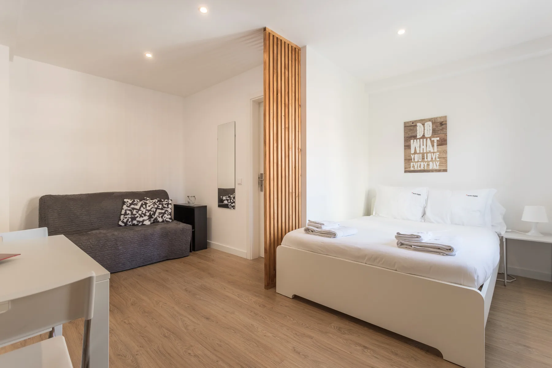 A studio room with a bed, a sofa, and a dining table.