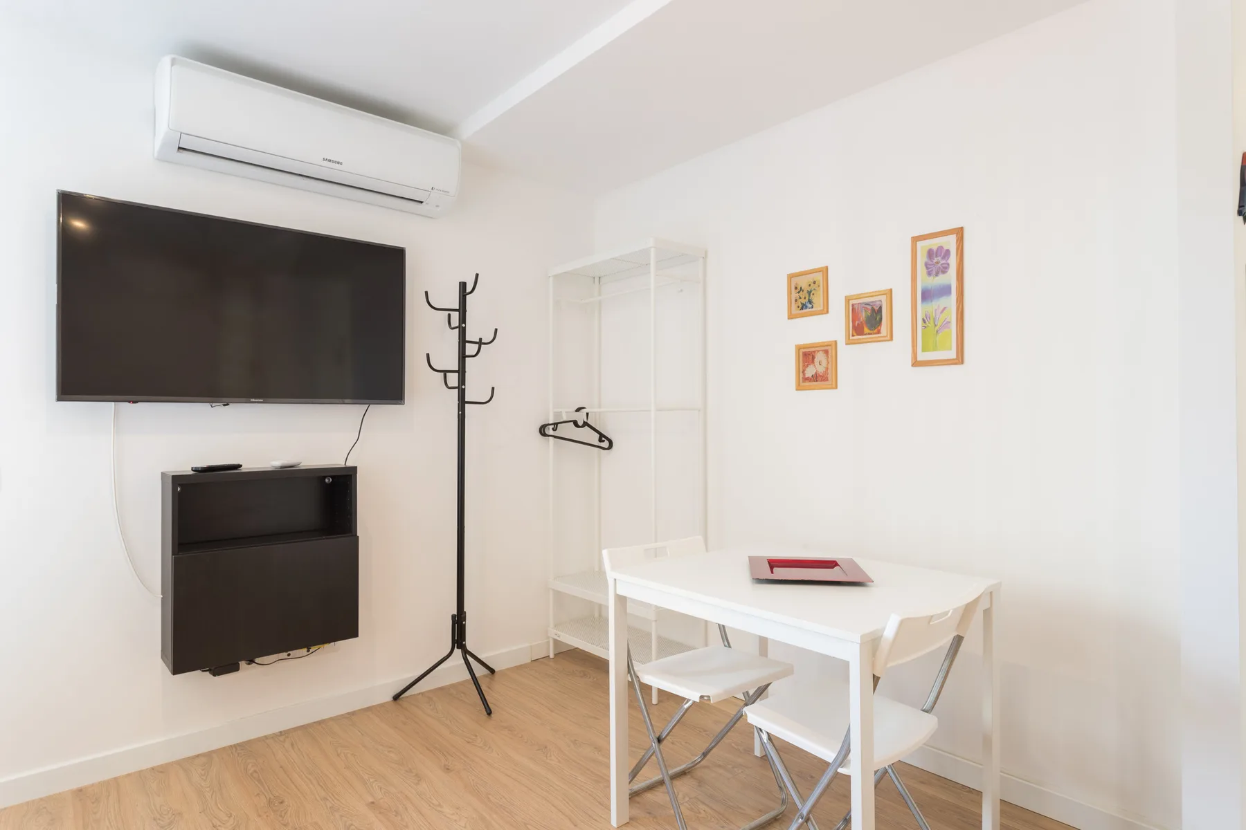 A bright dining area with a white table and wall-mounted television.