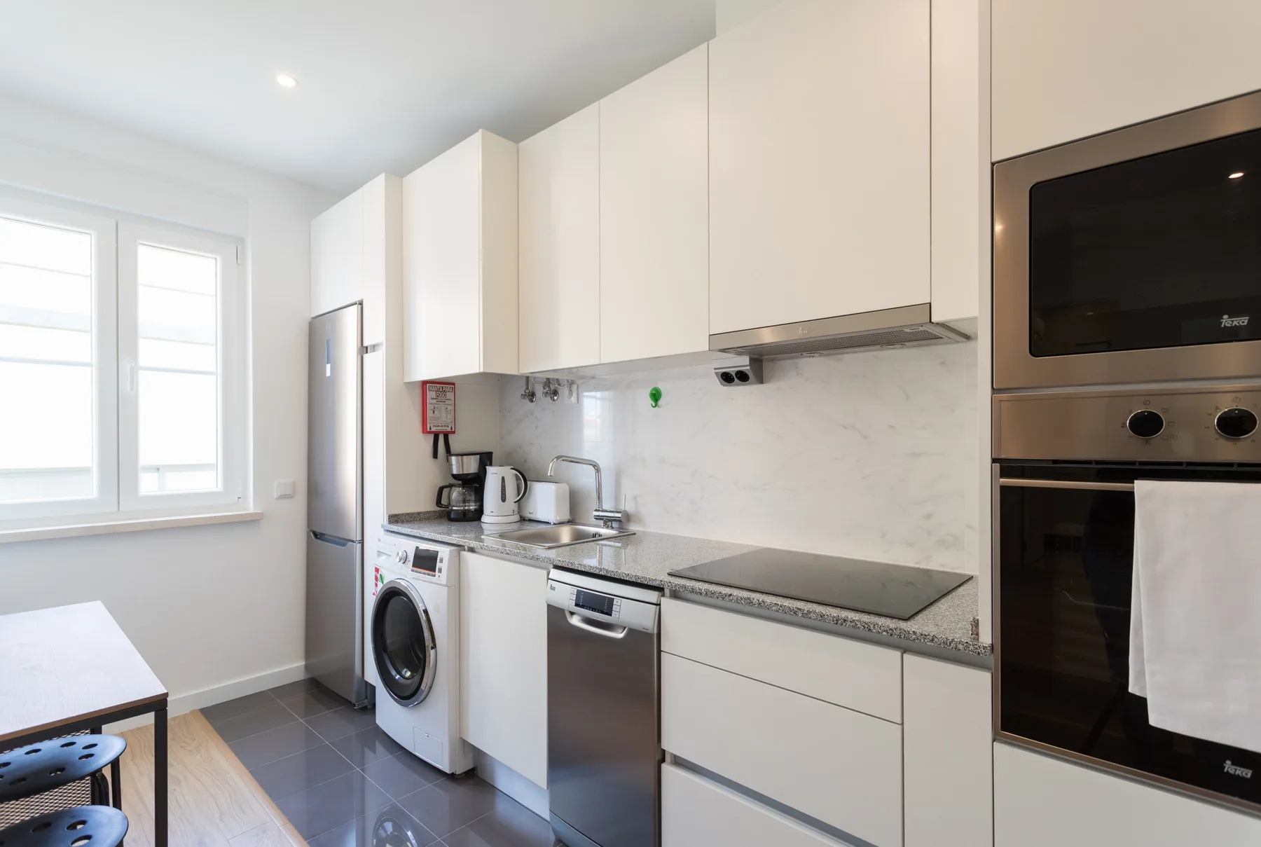 A compact kitchen with white cabinets, a cooktop, and a built-in oven.