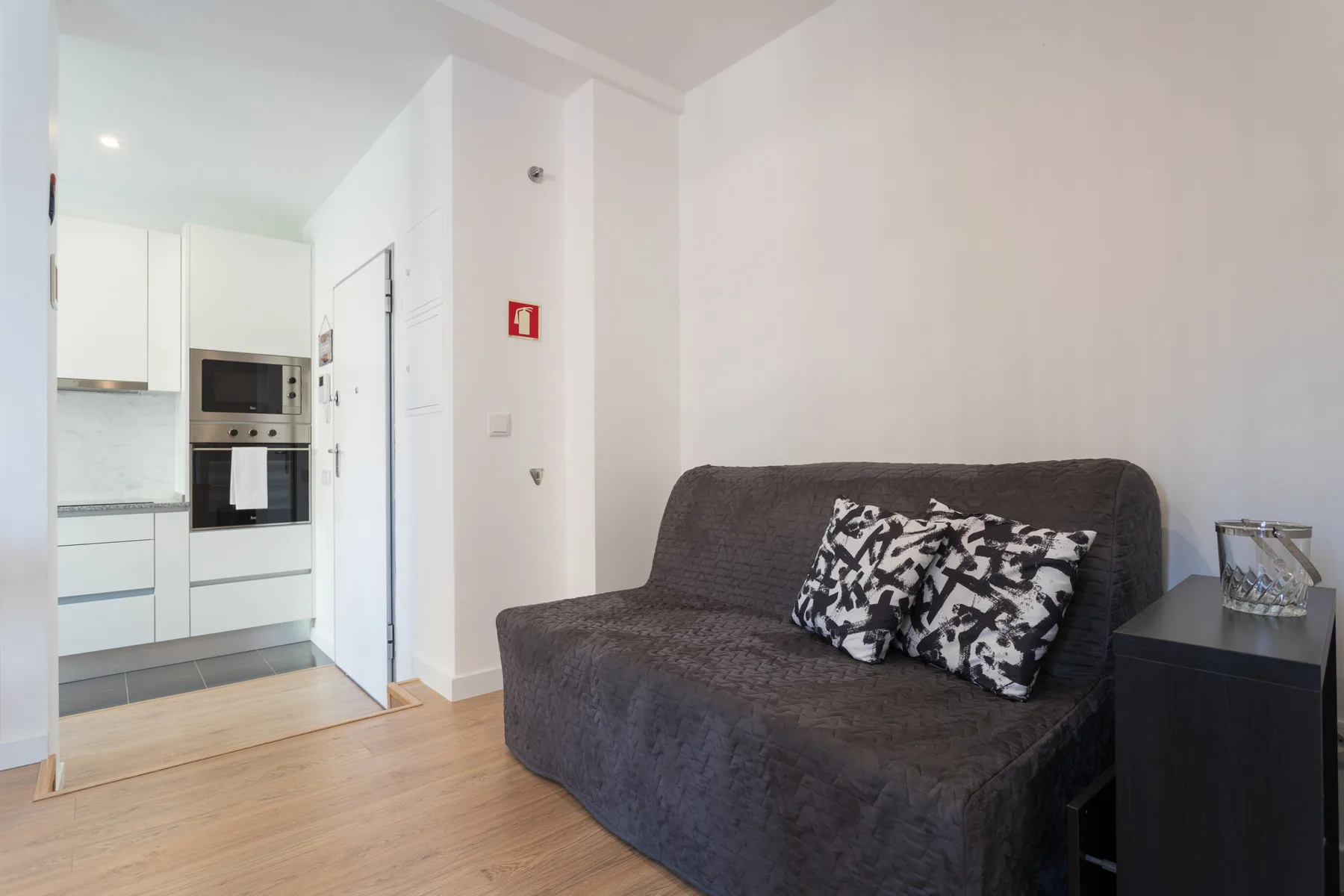 A living area with dark seating beside a compact kitchen.