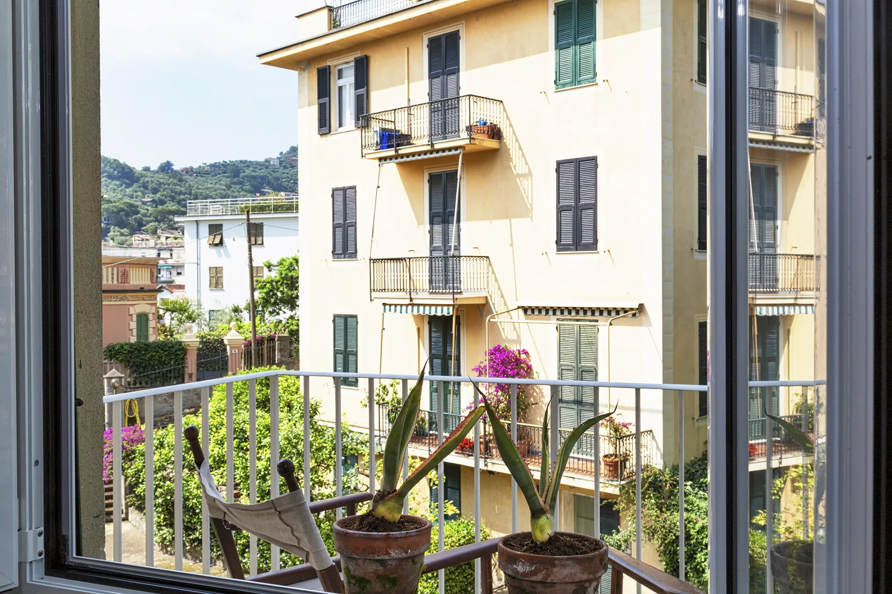 Un balcón da a un edificio de apartamentos vecino y a la vegetación circundante.