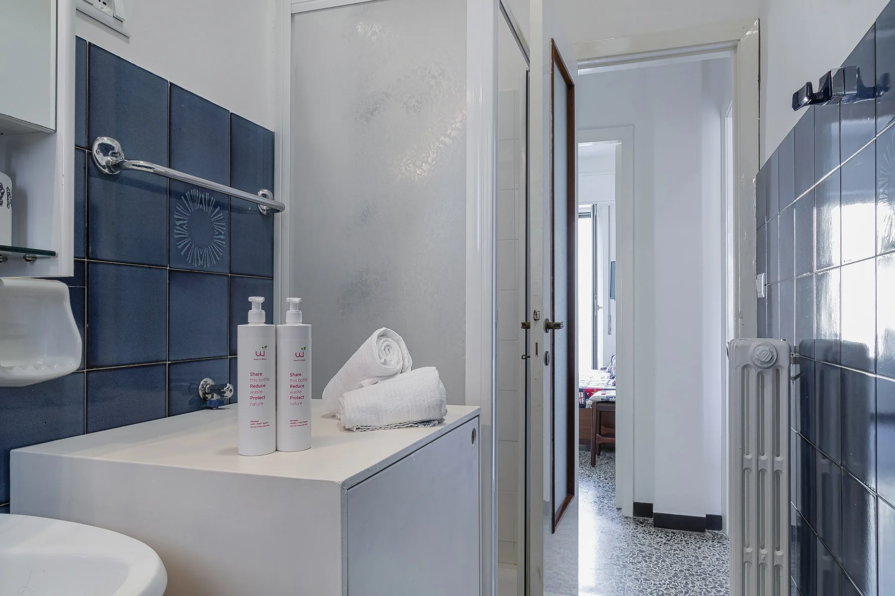 Un baño con un lavabo blanco junto a paredes de azulejos azul oscuro.