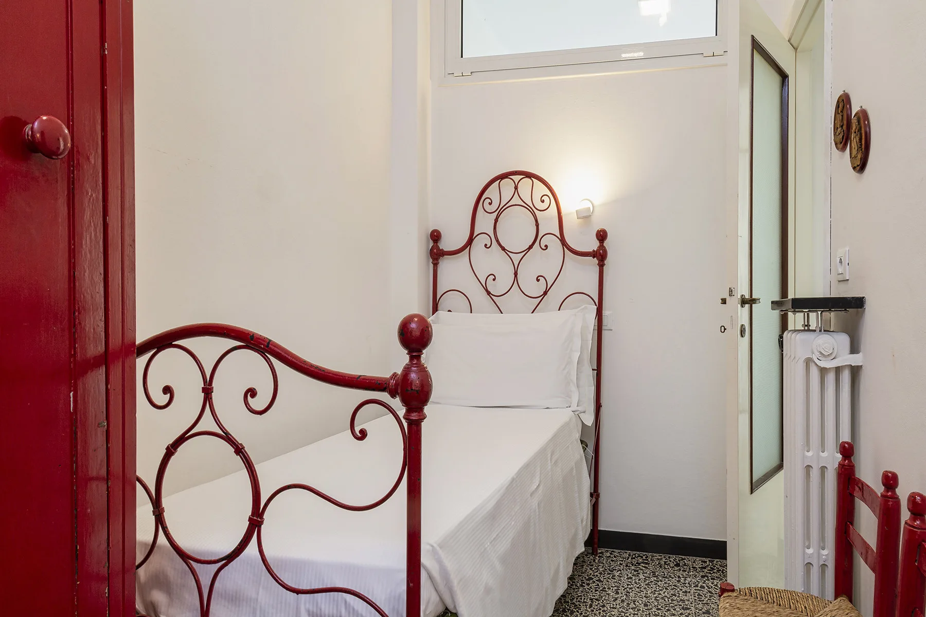 Un dormitorio con una cama individual junto a una ventana alta.