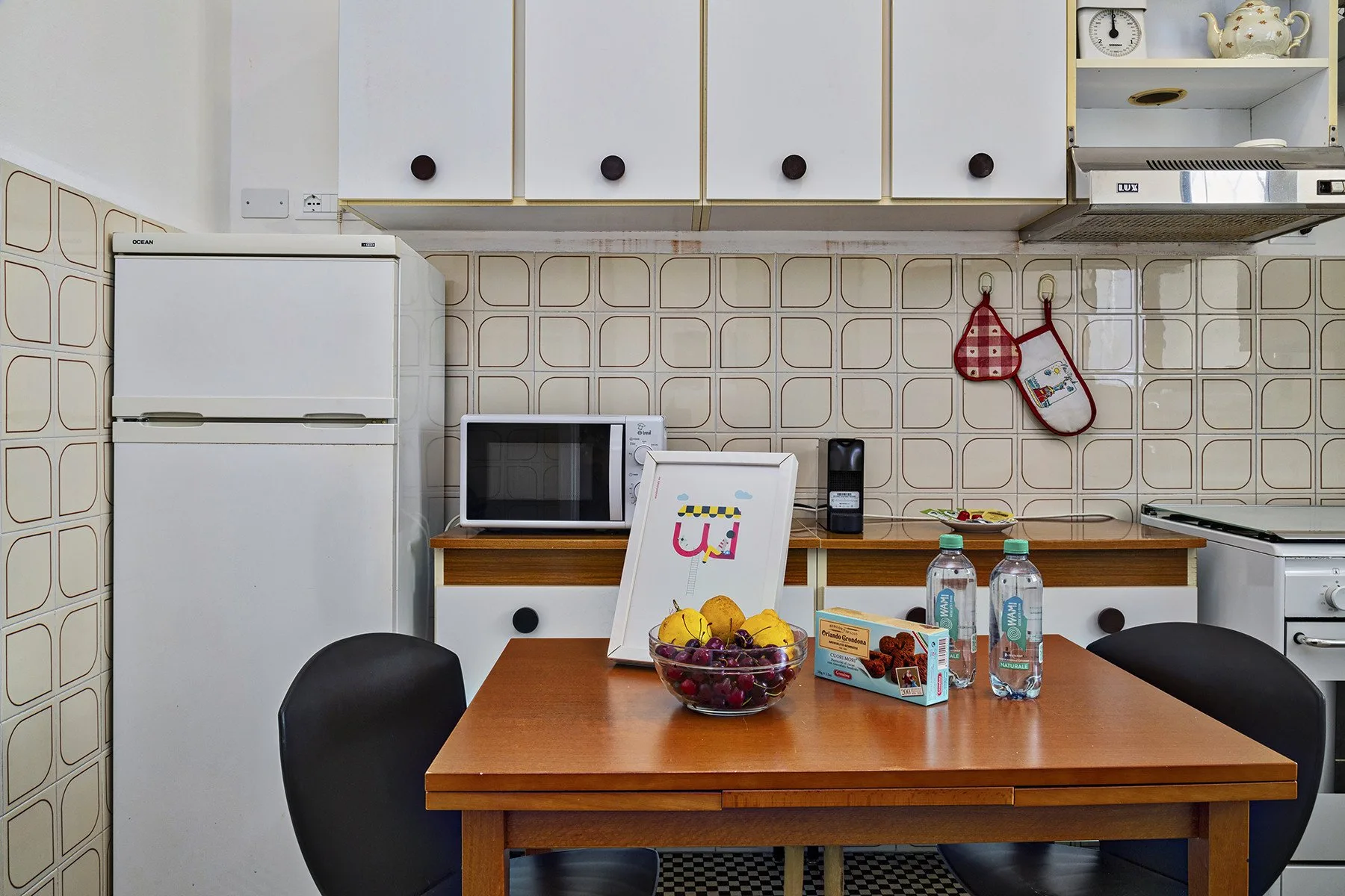 Una zona de comedor en la cocina con una mesa de madera, refrigerador y electrodomésticos de encimera.