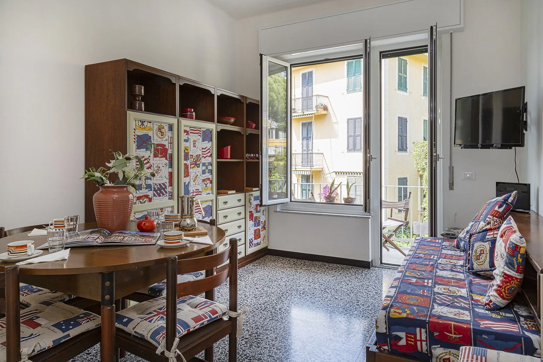 Un luminoso comedor y sala de estar con una mesa, asientos y puertas abiertas al balcón.