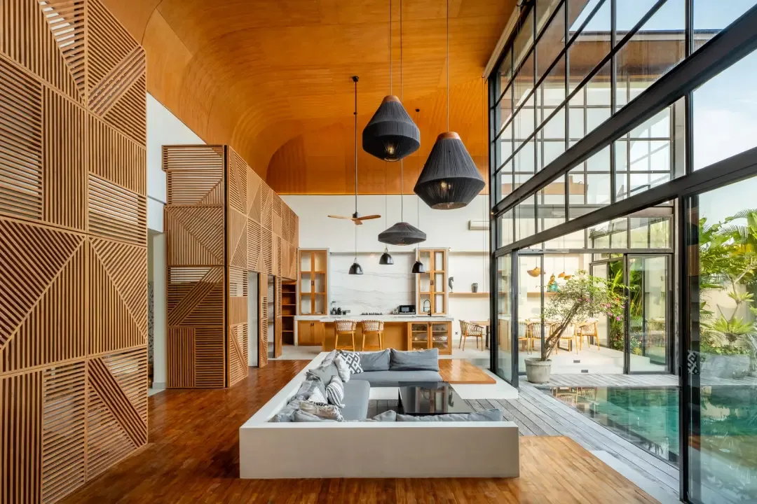 A modern open-plan living area with seating beside a glass wall and pool.