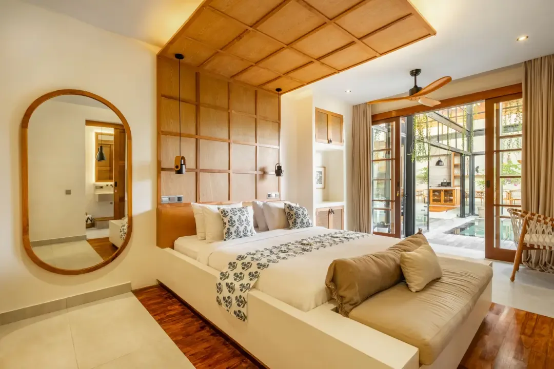 A bedroom with a bed, built-in seating, and glass doors opening to a patio.