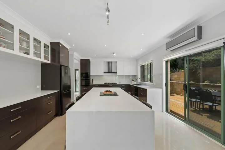 Una cocina moderna con una isla grande y puertas corredizas de vidrio que dan a un patio.