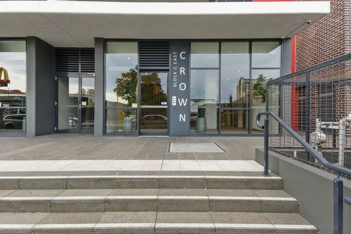 Entrada de un edificio moderno con puertas de vidrio y amplios escalones exteriores.