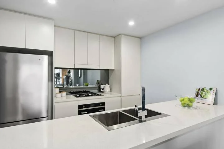 Una cocina moderna y luminosa con gabinetes blancos y una isla amplia.