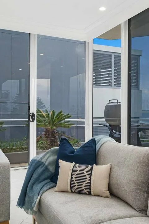Una sala de estar con asientos junto a ventanales y una pequeña palmera en maceta.