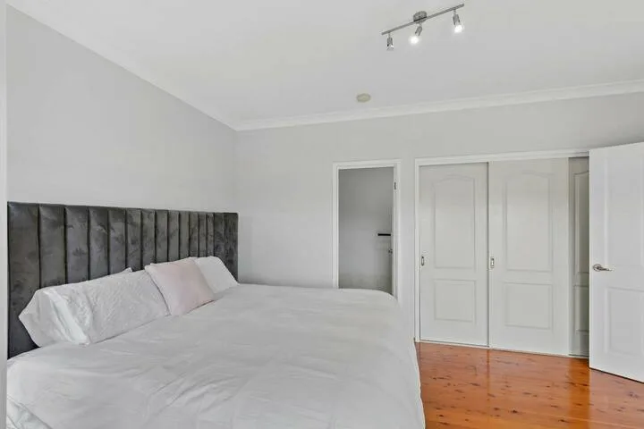 Un dormitorio con una cama, un cabecero oscuro y puertas blancas.