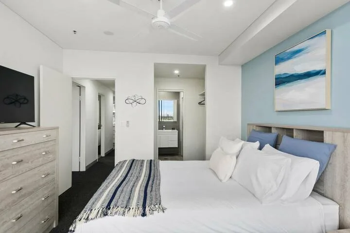 Un dormitorio con una cama tendida, una manta a rayas y arte en la pared.