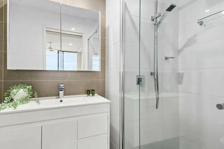 Un baño con lavabo, espejo y ducha con paneles de vidrio.