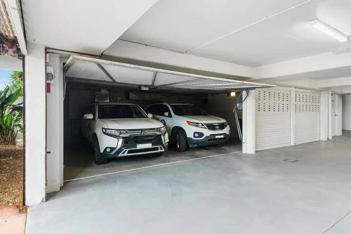 Una zona de estacionamiento cubierta con dos autos estacionados.