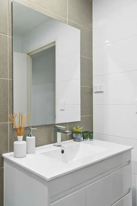 Un tocador de baño con un espejo rectangular y un lavabo blanco.