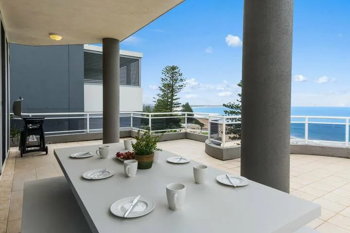 Una terraza con comedor en la azotea da al océano, con una mesa preparada para comer.