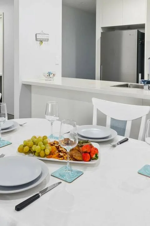 Una mesa está preparada con platos, vasos y una bandeja de fruta y bollería.