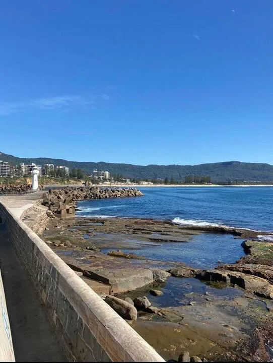 Un paseo costero ofrece vistas de una orilla rocosa y aguas azules.