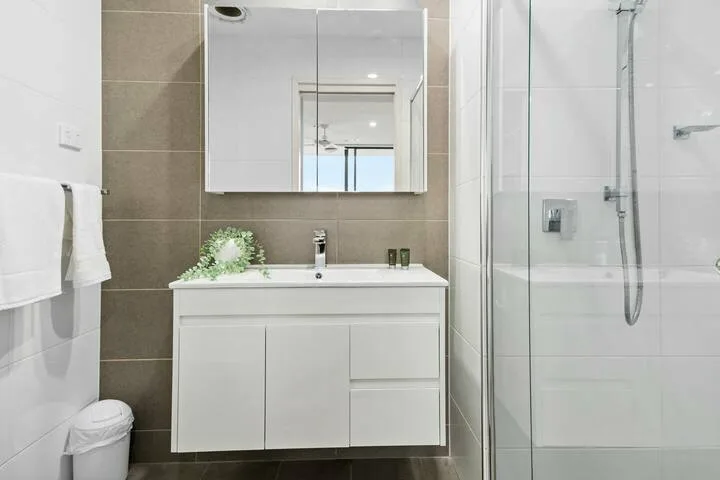 Un baño con un mueble de lavabo blanco, un armario con espejo y una ducha de vidrio.