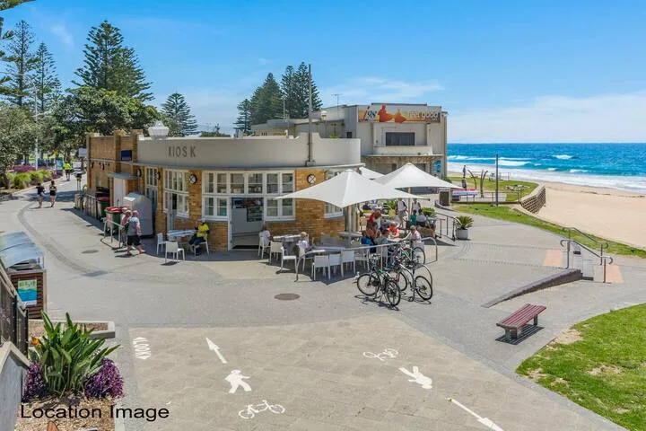 Una cafetería junto al mar tiene mesas al aire libre frente a la playa y el océano.