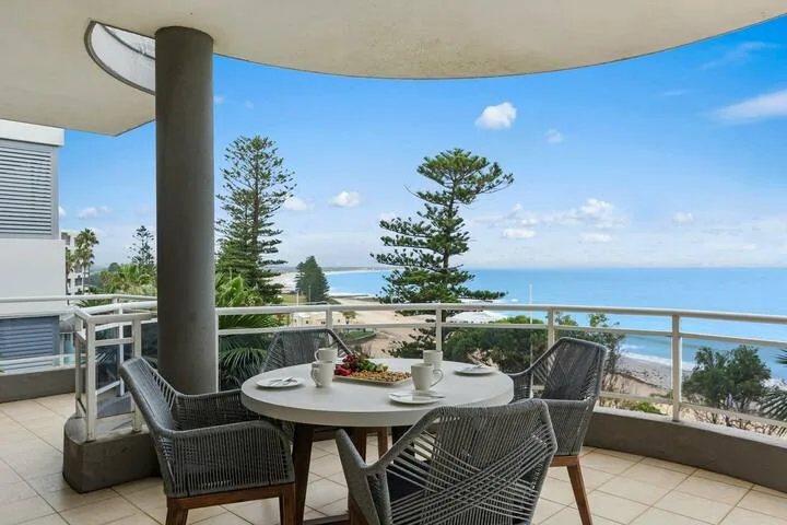 Una zona de comedor en el balcón tiene vistas al mar, con mesa y asientos al aire libre.