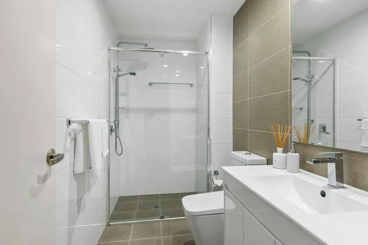 Un baño con azulejos, una ducha de vidrio y un lavabo con mueble.