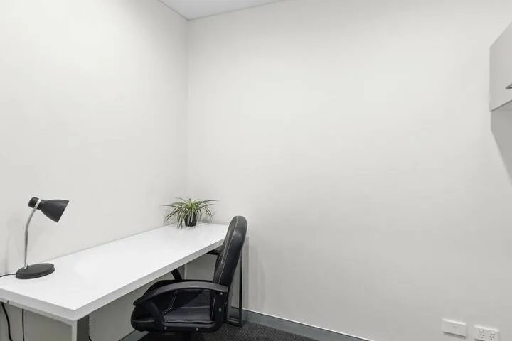 Un pequeño espacio de oficina con escritorio, silla y lámpara de mesa.