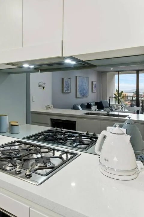 Una cocina moderna con estufas y una encimera junto a una luminosa sala de estar.