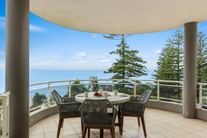 Comedor al aire libre en una terraza curva con vistas al mar.