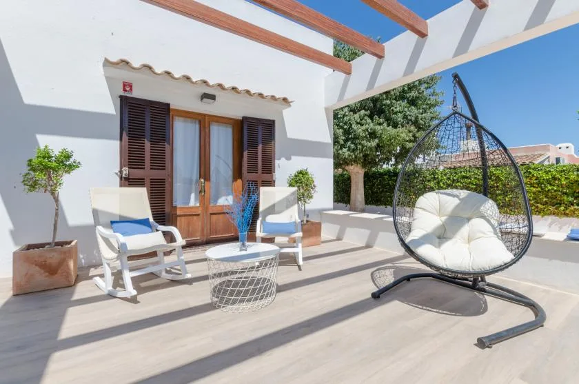 Un patio soleado con asientos al aire libre y una silla colgante.