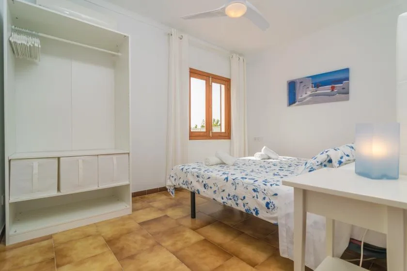 Un dormitorio con una cama, un armario empotrado y una ventana con marco de madera.