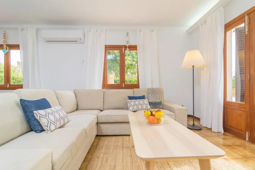 Una sala luminosa con una zona de asientos en esquina y una mesa de centro alargada.