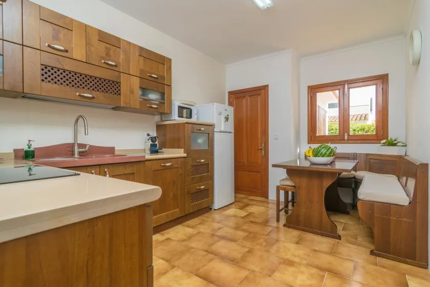 Una cocina con armarios de madera, una encimera y un pequeño comedor junto a la ventana.