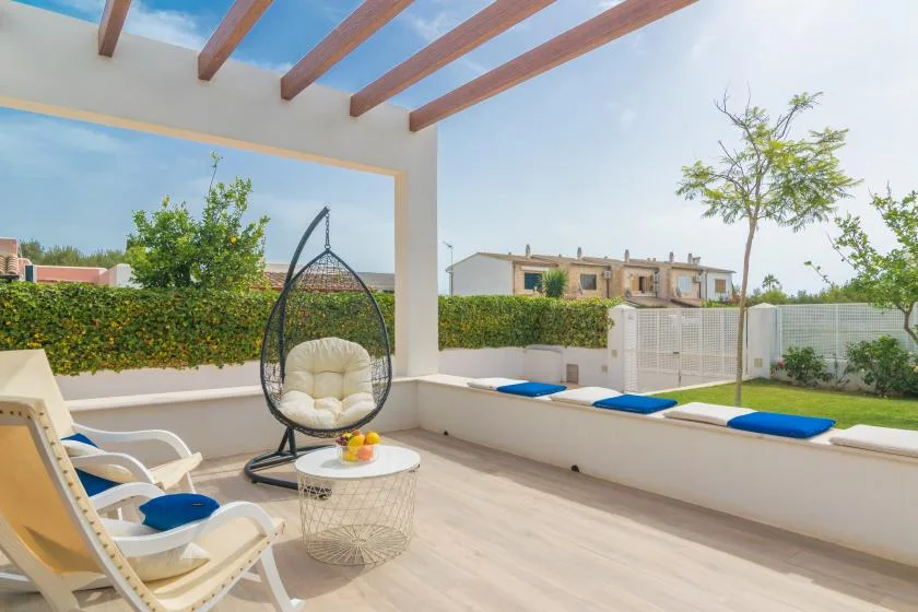 Un patio soleado con asientos, una mesa pequeña y un seto frondoso.