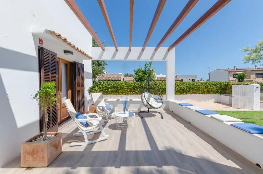 Una terraza soleada en la azotea con asientos y una pérgola que proyecta largas sombras.