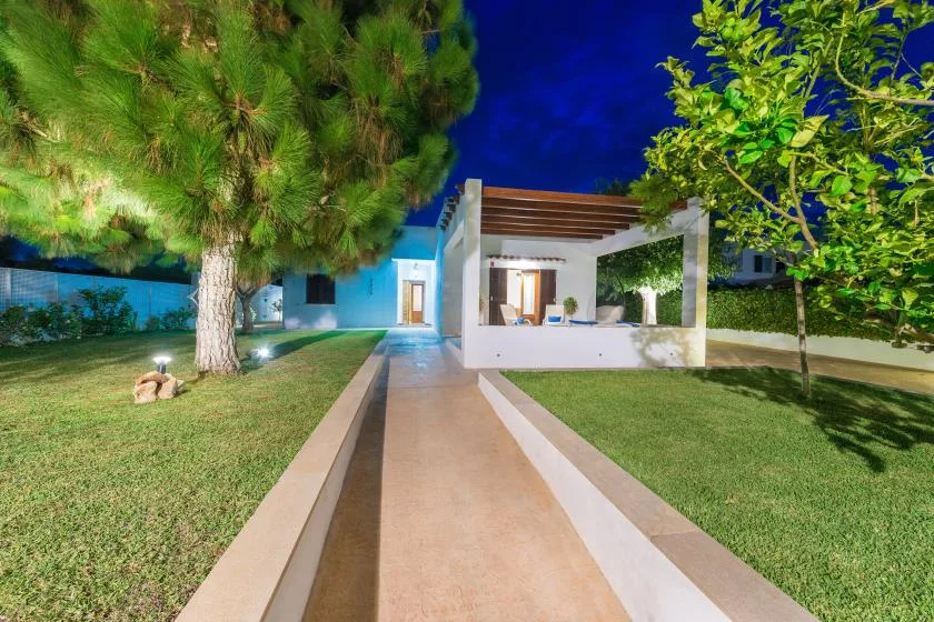 Un sendero de jardín lleva a una zona de estar exterior cubierta junto a la casa.
