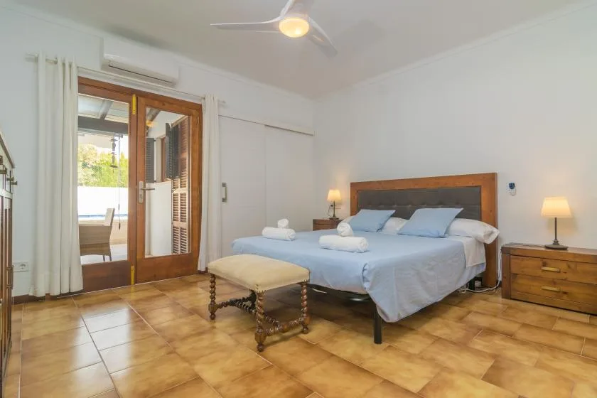 Un dormitorio con una cama grande, mesitas de noche y un banco acolchado.