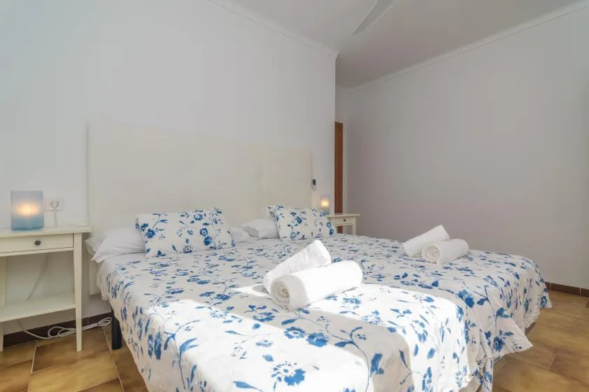 Un dormitorio con dos camas cubiertas con ropa de cama floral blanca y azul.