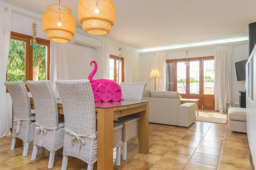 Una luminosa zona de comedor y estar tiene una mesa de madera y asientos claros.