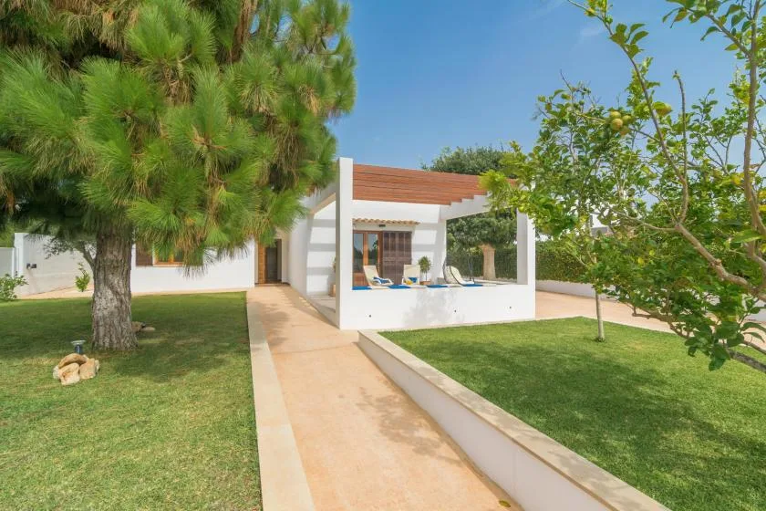 Un sendero del jardín lleva a una zona blanca de asientos al aire libre junto a la casa.